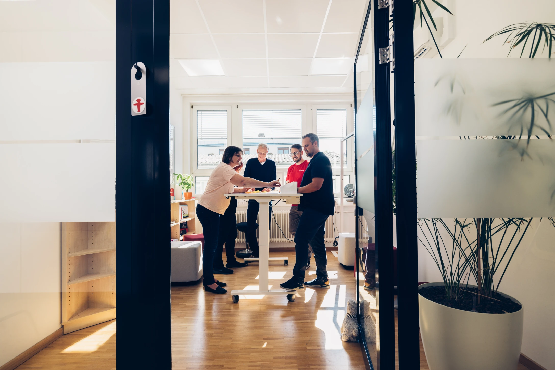 Eine Gruppe von Menschen, die sich in einem Büro um einen Tisch versammelt, um zu diskutieren und zusammenzuarbeiten.