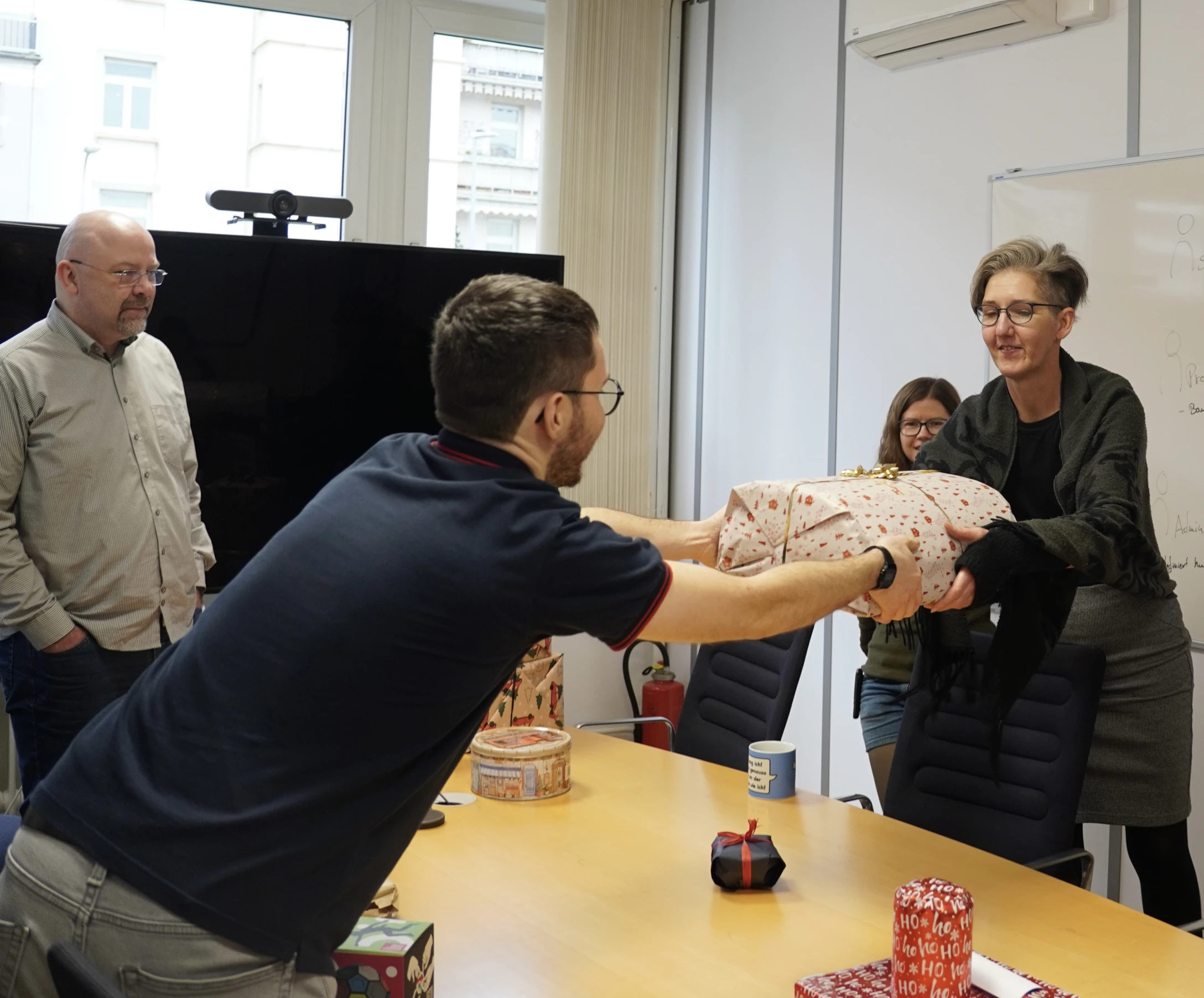 punkt.de MItarbeitende beim Wichteln. Ein Kollege übergibt ein Geschenk an eine Kollegin.